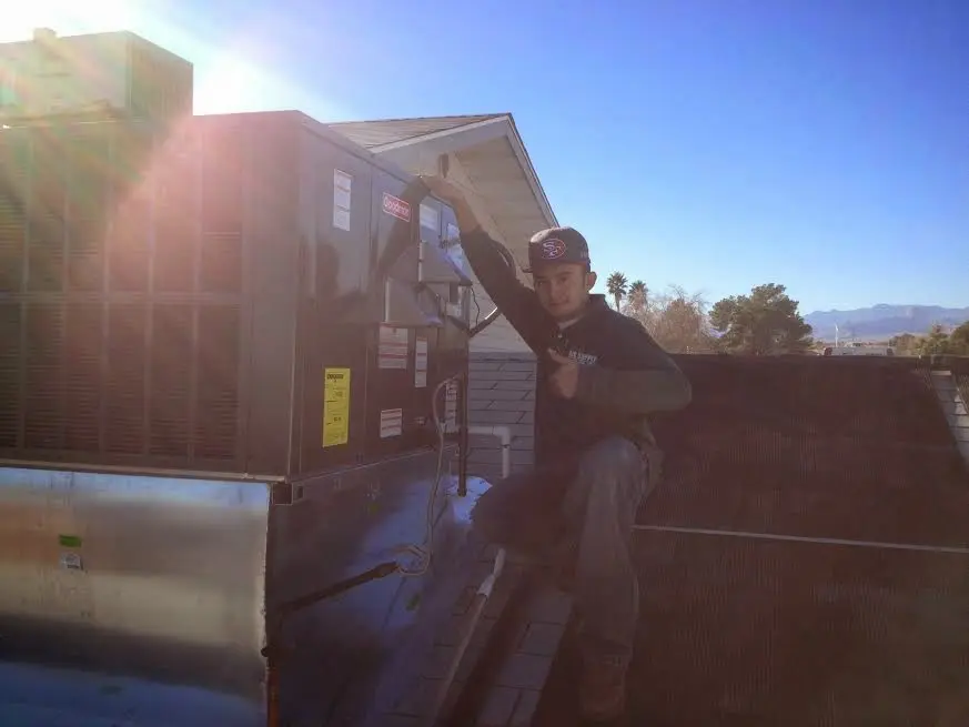 HVAC technician performing Air Duct Cleaning on a rooftop unit in Cambridge